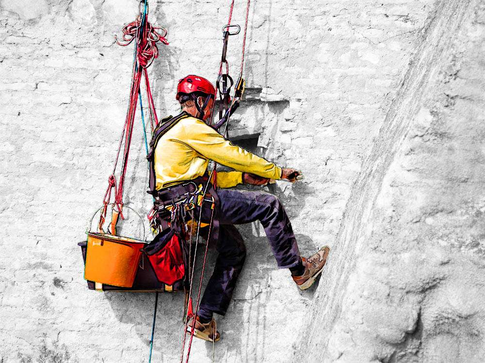 Höhenarbeiter bei der Durchführung von Maurerarbeiten in Seilzugangstechnik